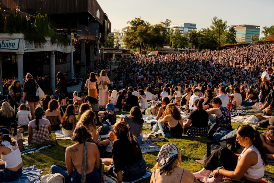 concertgoers seated on the lawn in front of a pavilion