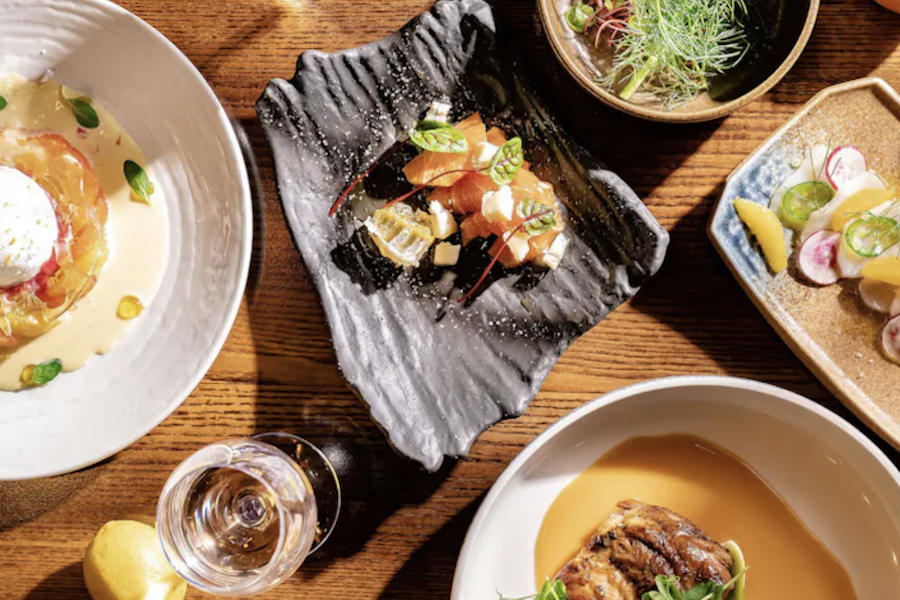 A top-down view of various sushi dishes on a wooden table, showcasing a variety of beautifully presented food items.