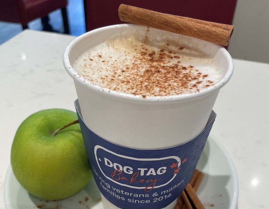 A spiced latte from Dog Tag Bakery, topped with cinnamon and served alongside a green apple.