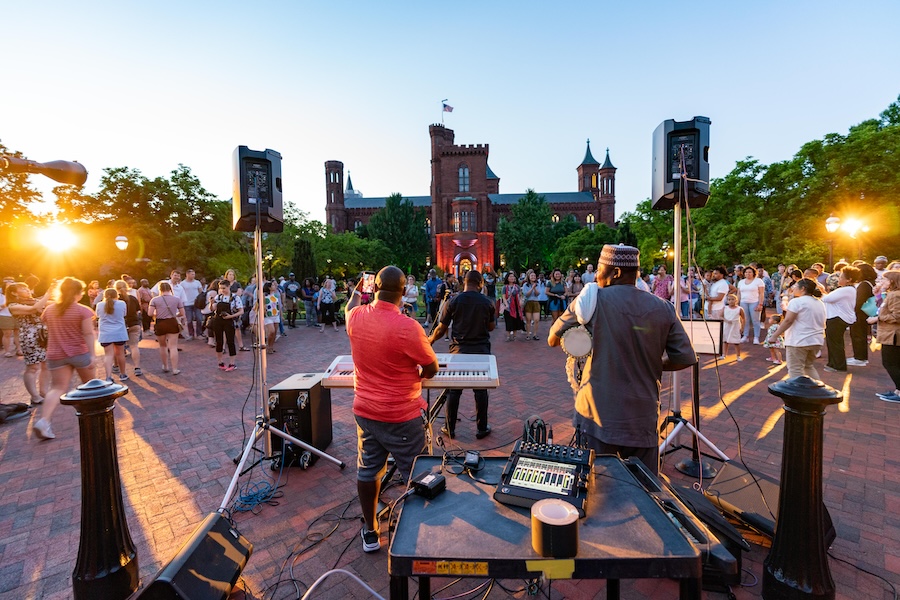 A live band performs at sunset during a lively outdoor event at the Smithsonian Castle in Washington, DC.