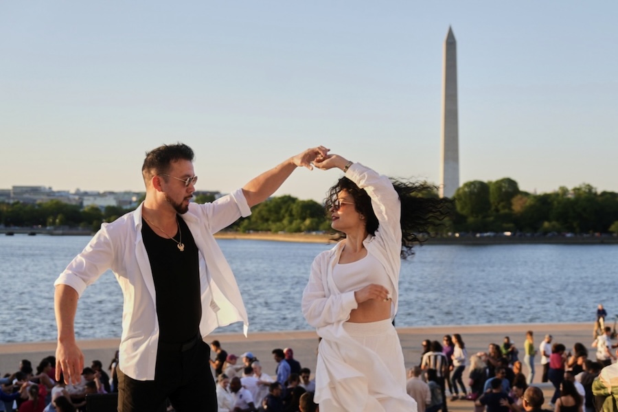 Dos personas bailan con el Monumento a Washington al fondo.