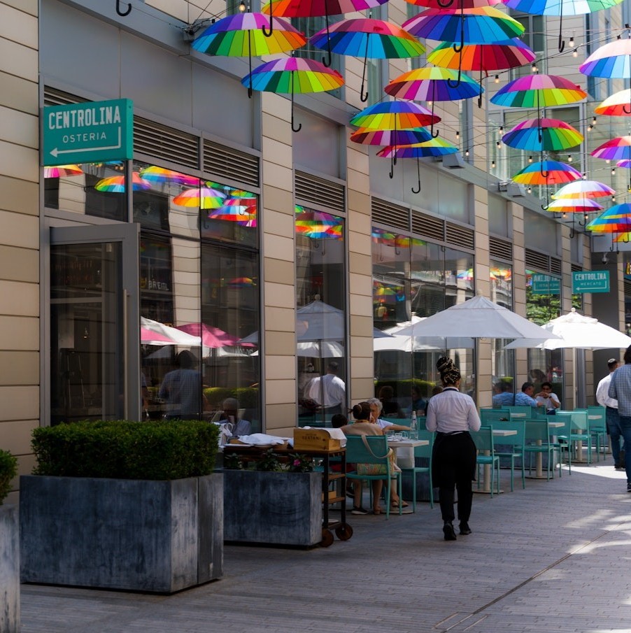 Outdoor seating with rainbow umbrellas in an alley
