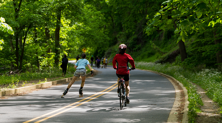 A person rollerblading and another biking in Rock Creek Park