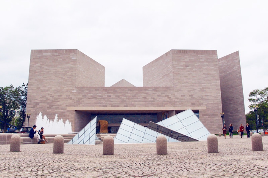 The exterior of the National Gallery of Art's East Building, featuring modern architecture with angular glass pyramids and a fountain in the foreground.