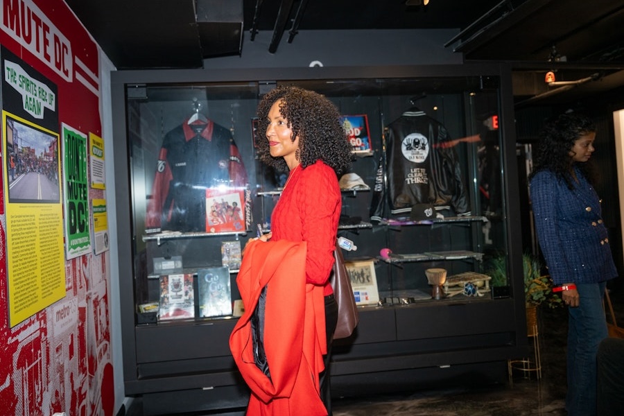 A visitor in a red sweater observes a display of go-go memorabilia, including jackets, albums and historic photos.