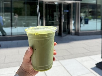 A hand holds up a to-go matcha
