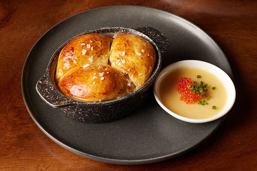 A modern plate with a cast iron pan of salted bread and a modern, caviar-topped sauce.