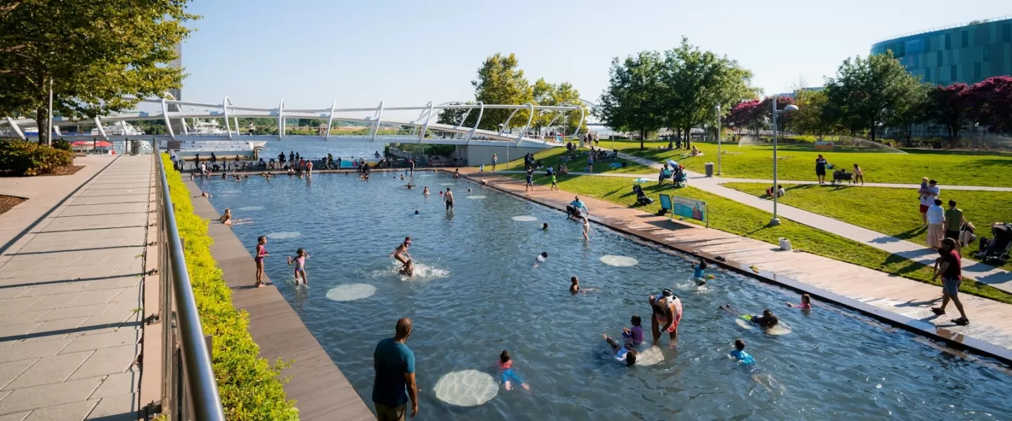 Kids play in a massive splash pool at a public park in the summertime. 