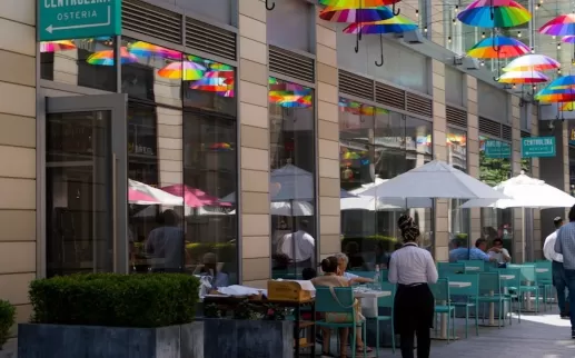 Outdoor seating with rainbow umbrellas in an alley
